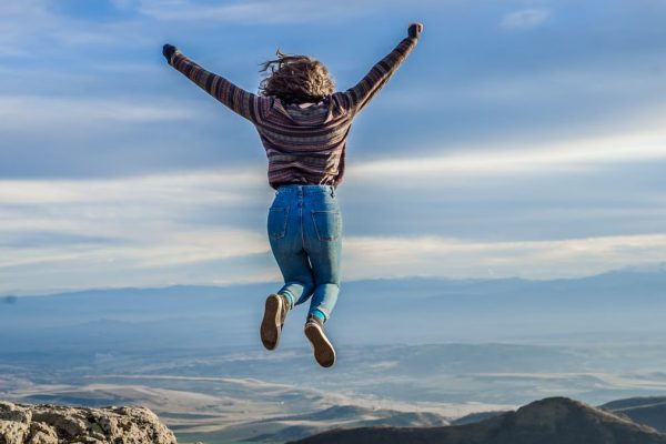 Person jumping on a mountain peak, celebrating adventure and freedom.